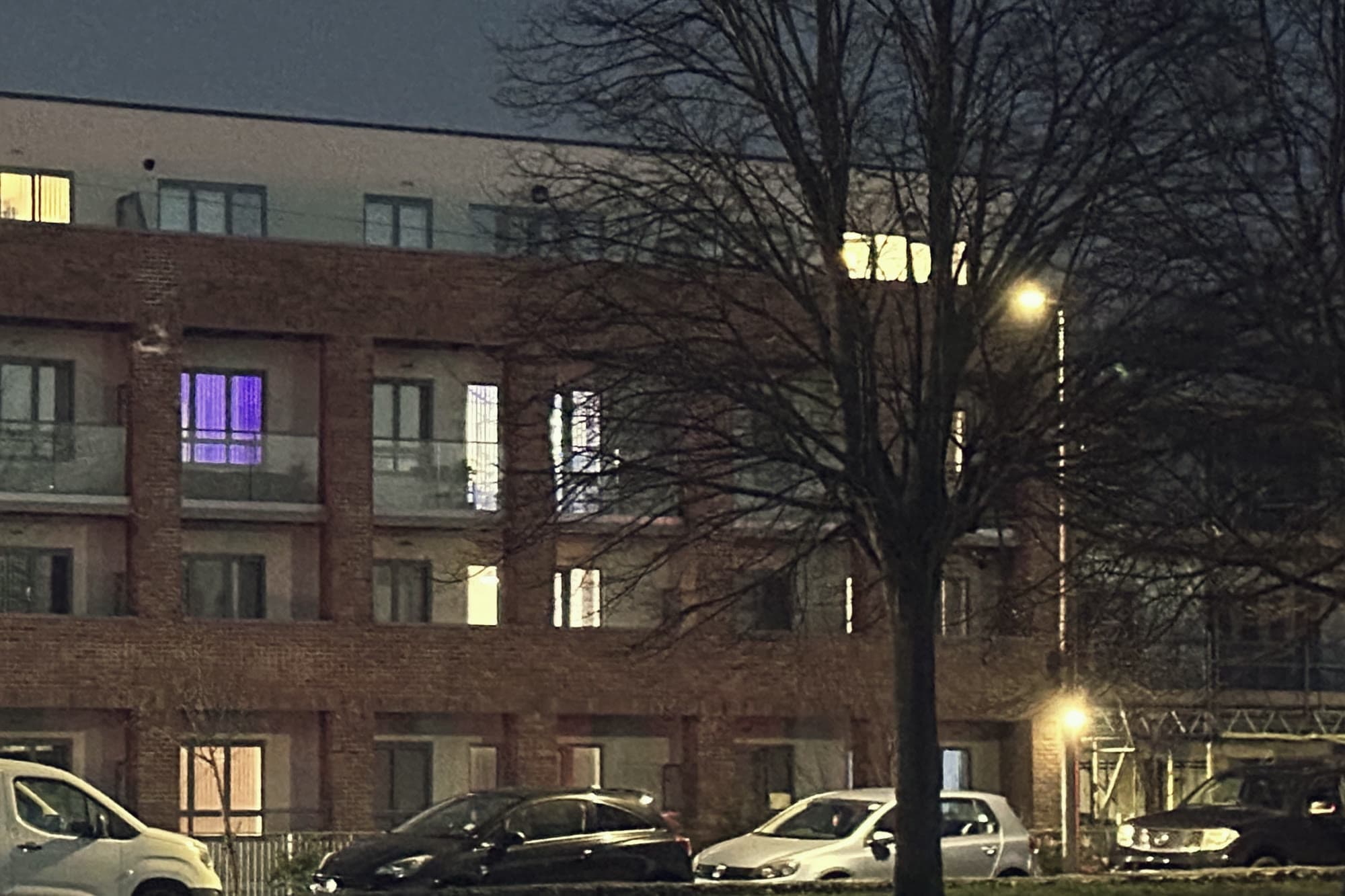 A brick apartment building at night with lit windows
