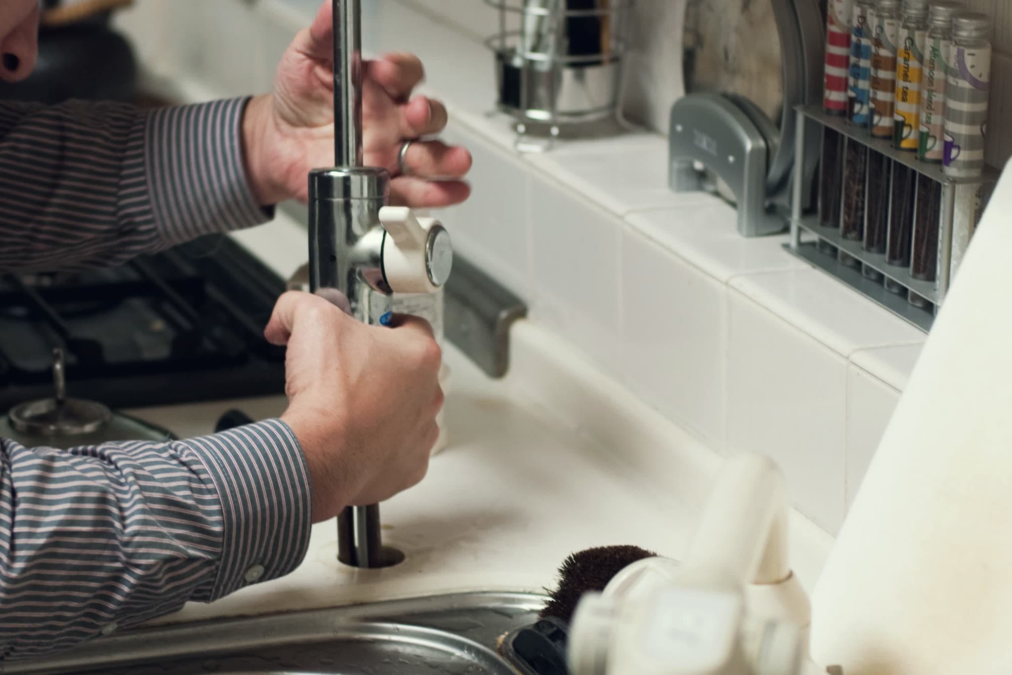 Hands fitting a new tap at a kitchen sink
