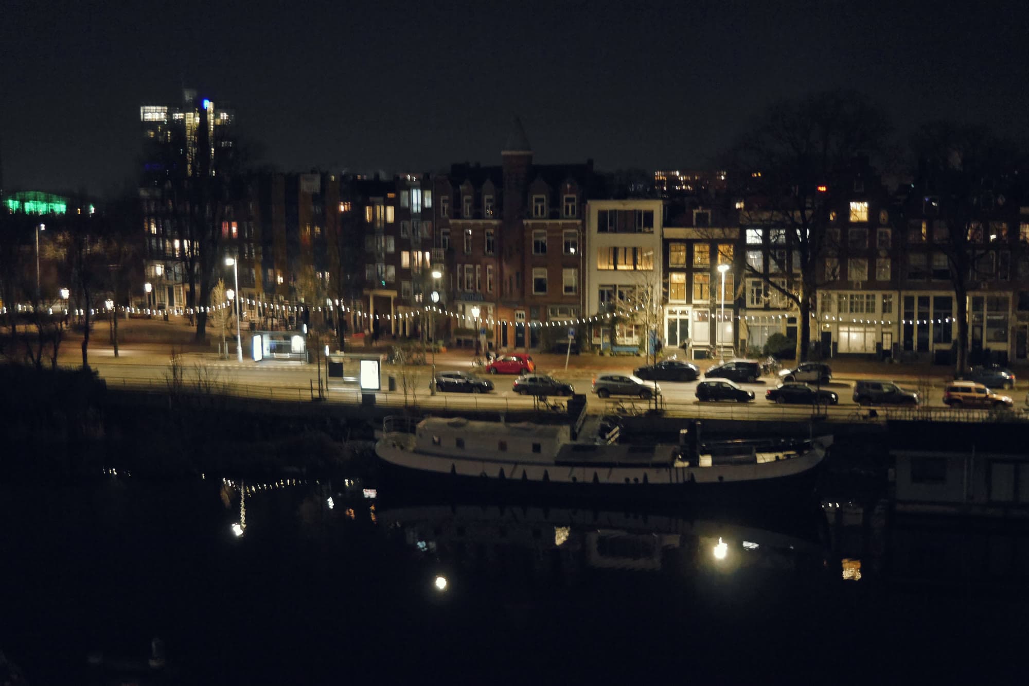 A street of lit row houses beside a canal at night